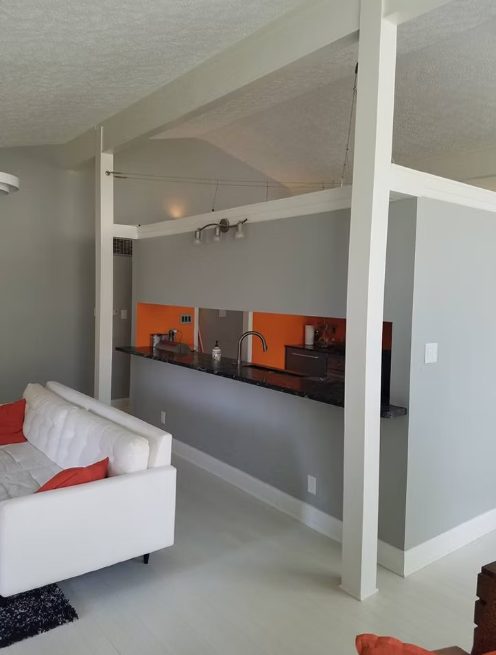 A living room with a white couch and orange pillows