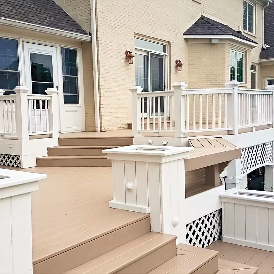 A large deck with stairs and a white railing in front of a house.