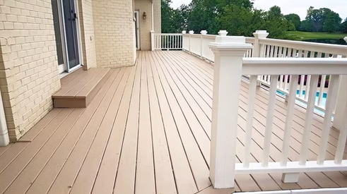 A large deck with a white railing and stairs leading to it.