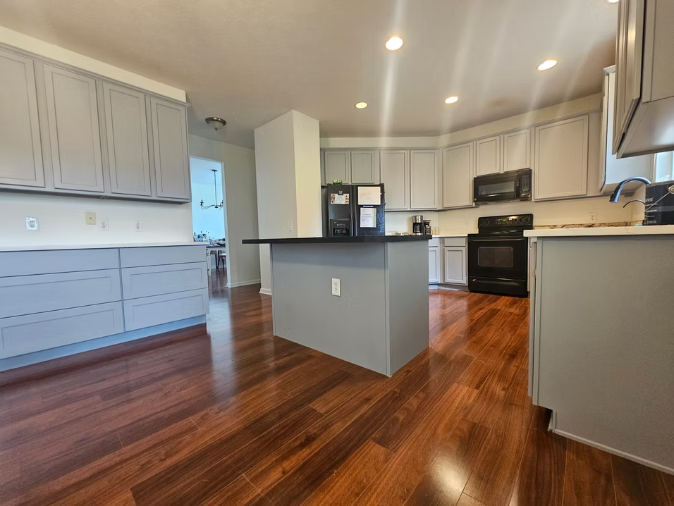 A kitchen with a large island in the middle and hardwood floors.