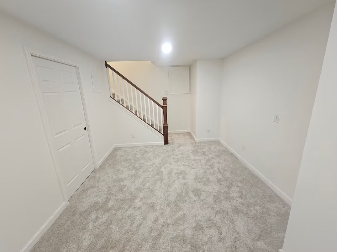 An empty basement with stairs leading up to the second floor.