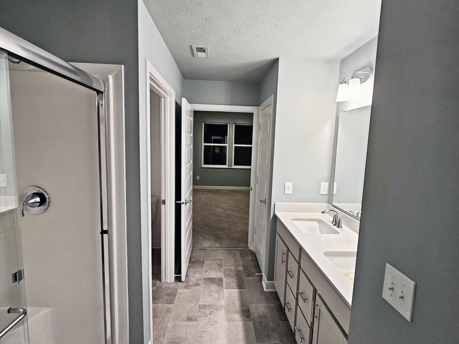 A bathroom with two sinks and a walk in shower.