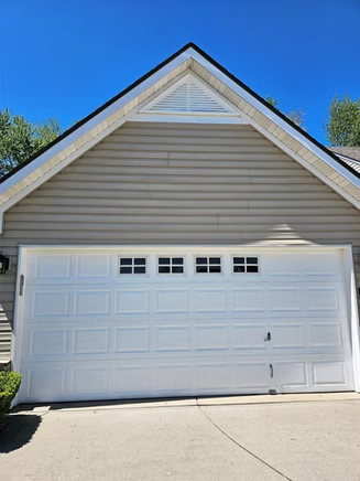 A white garage door is sitting on the side of a house.