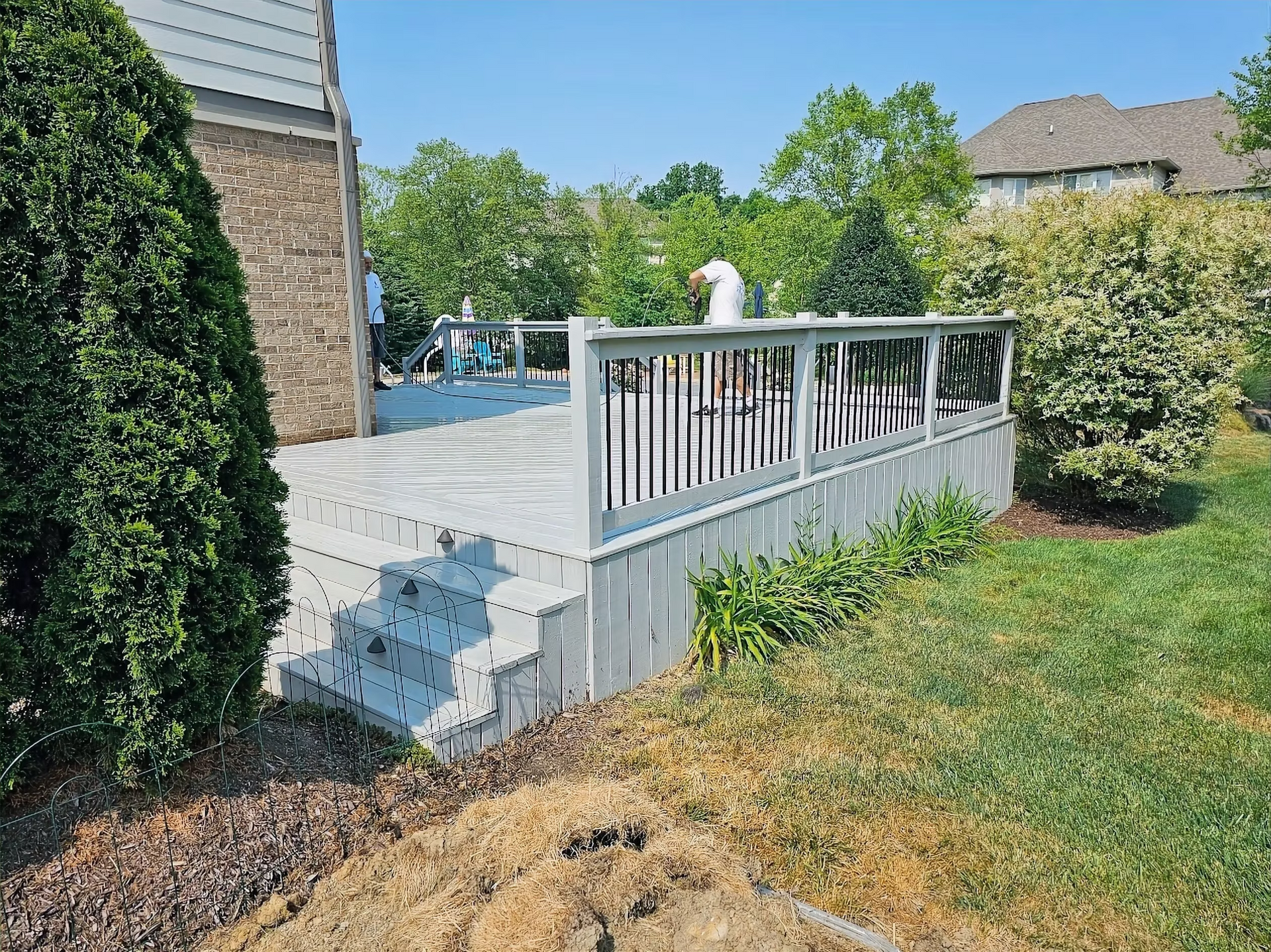A large white deck with stairs is in the backyard of a house.