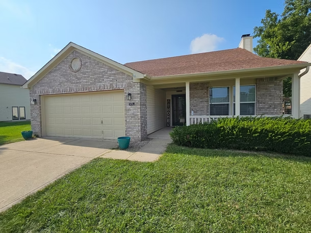 A brick house with a large garage and a porch.