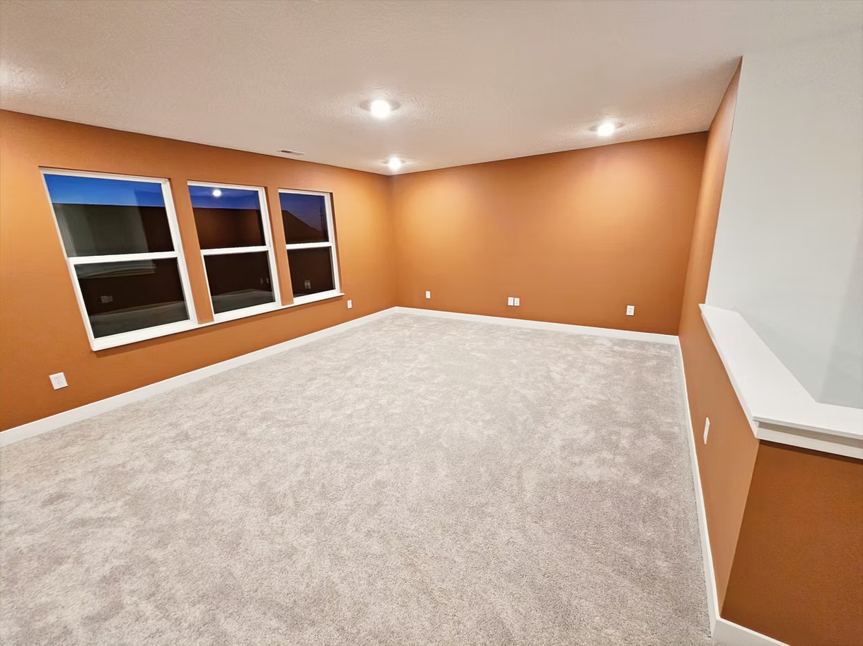 A large empty room with a lot of windows and carpet.