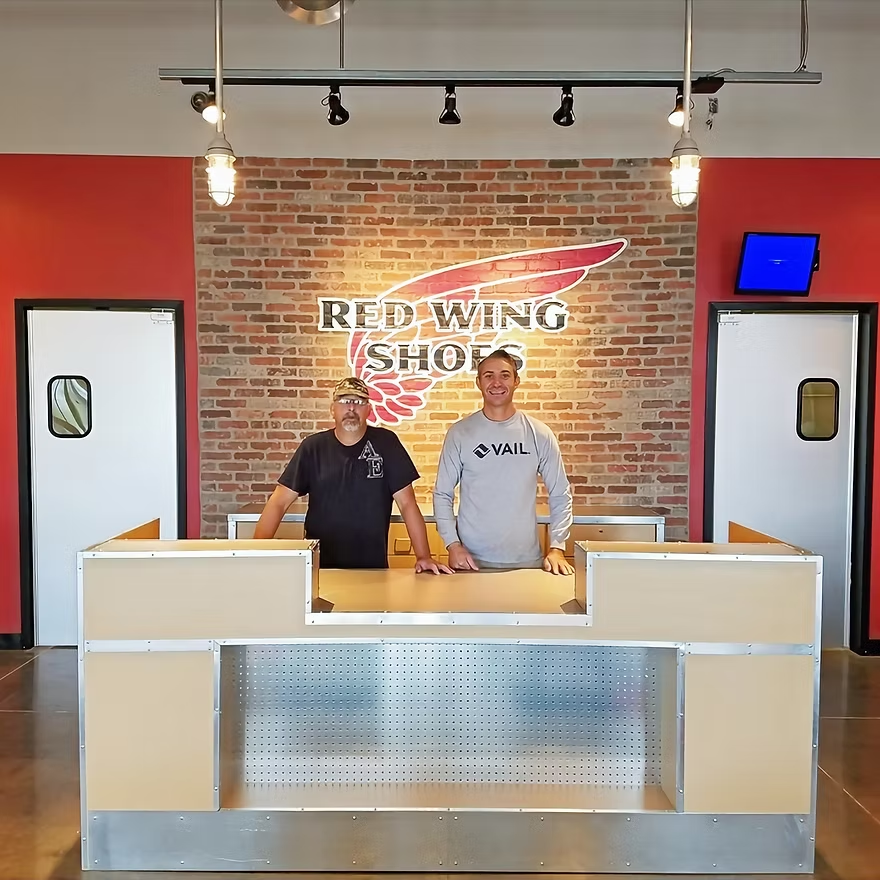 Two men standing in front of a red wing shop counter