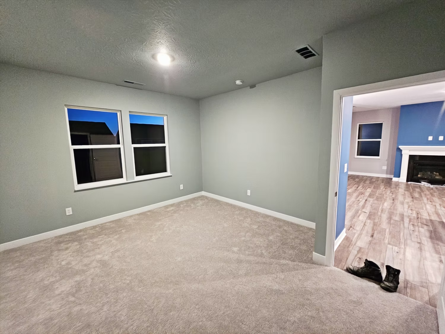 An empty room with a fireplace and two windows.