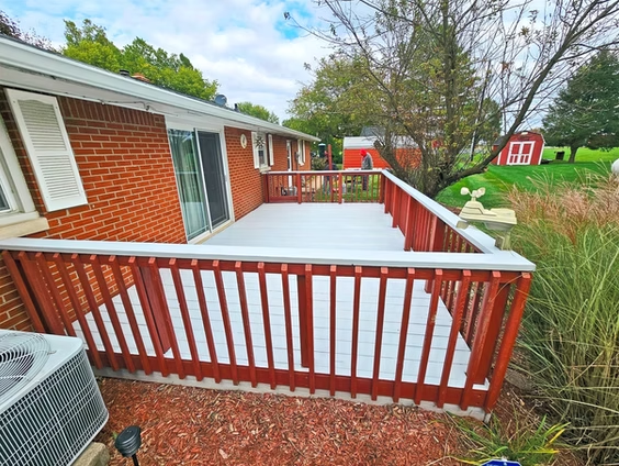 A brick house with a white deck and a red railing