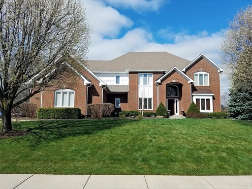 A large brick house with a large lawn in front of it