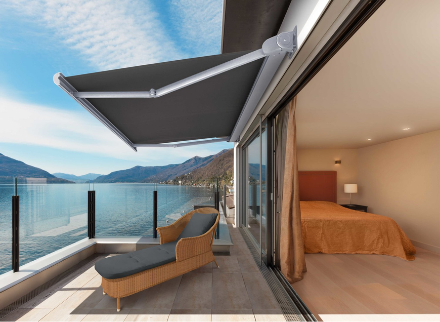 A balcony with a chair and a bed overlooking a lake.