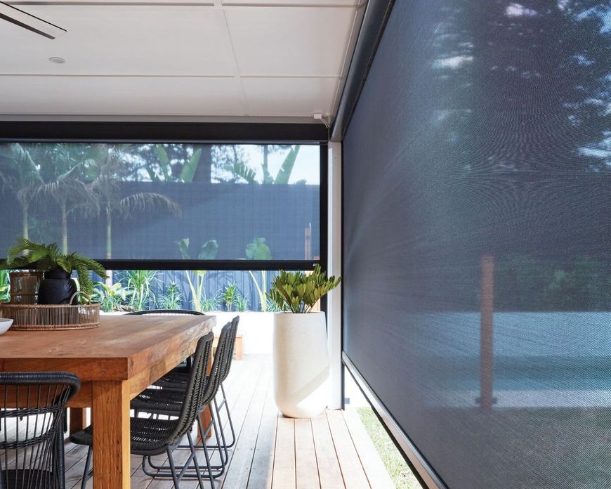 A dining room with a wooden table and chairs and a large window.