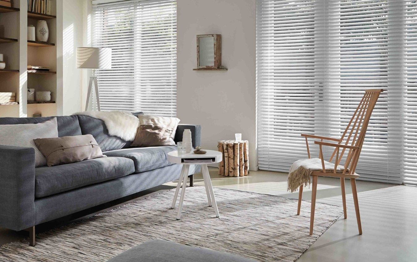 A living room with a couch , chair , table and blinds.