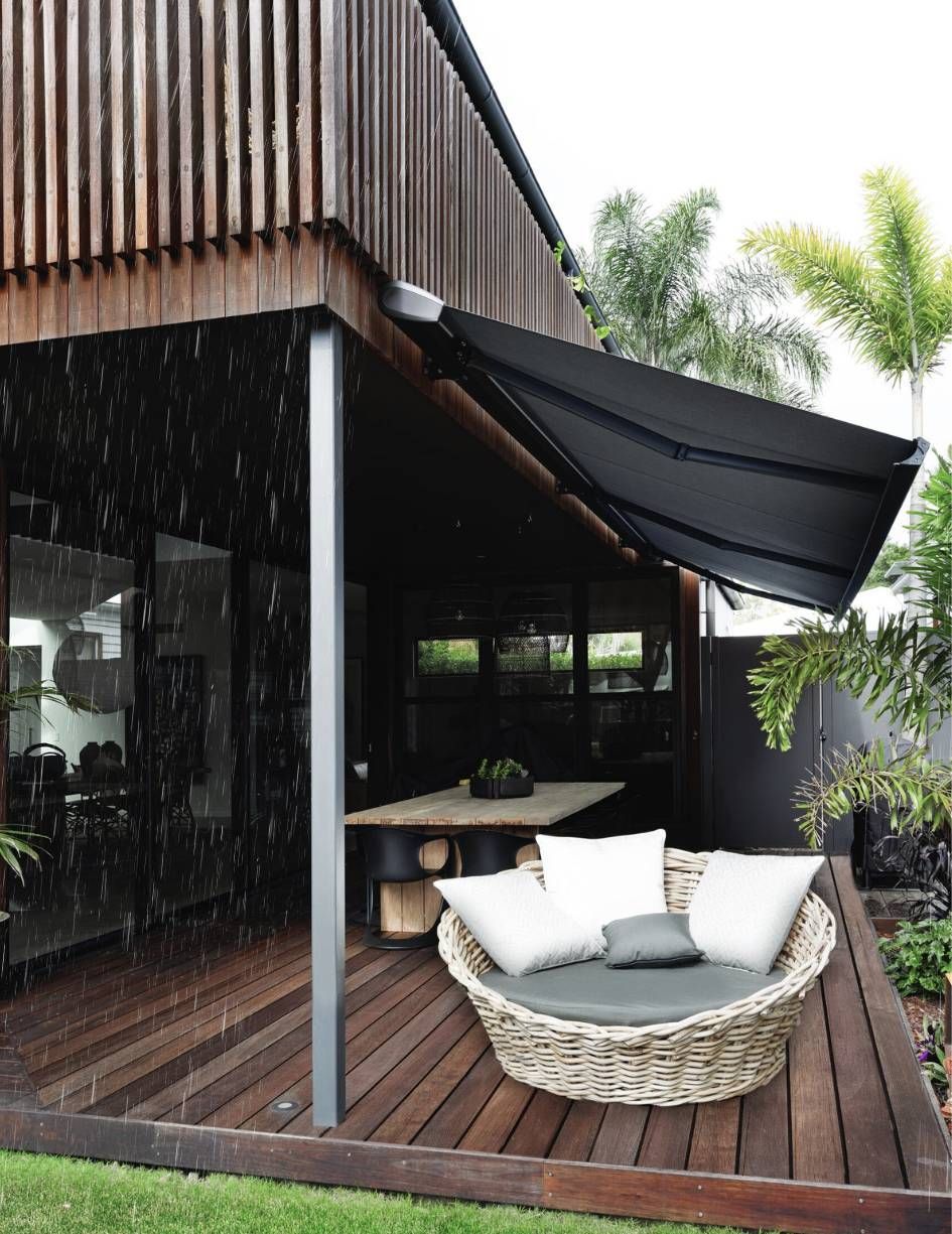 A wicker chair sits on a wooden deck under an awning