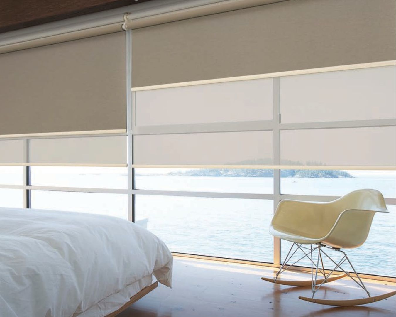 A bedroom with a bed and a rocking chair with a view of the ocean.