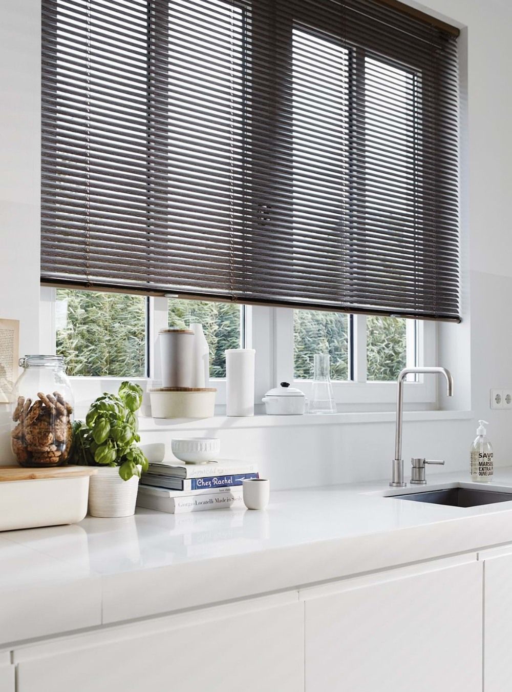 A kitchen with a sink and a window with blinds on it.