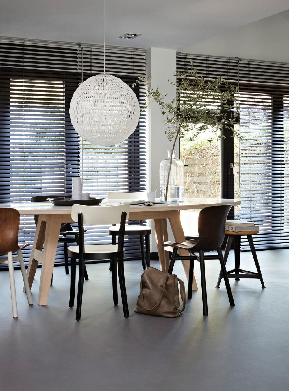 A dining room with a table and chairs and blinds on the windows