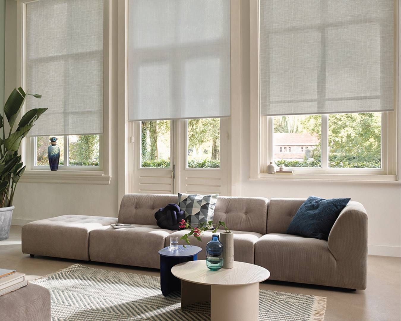 A living room with a couch , two tables , and two windows.