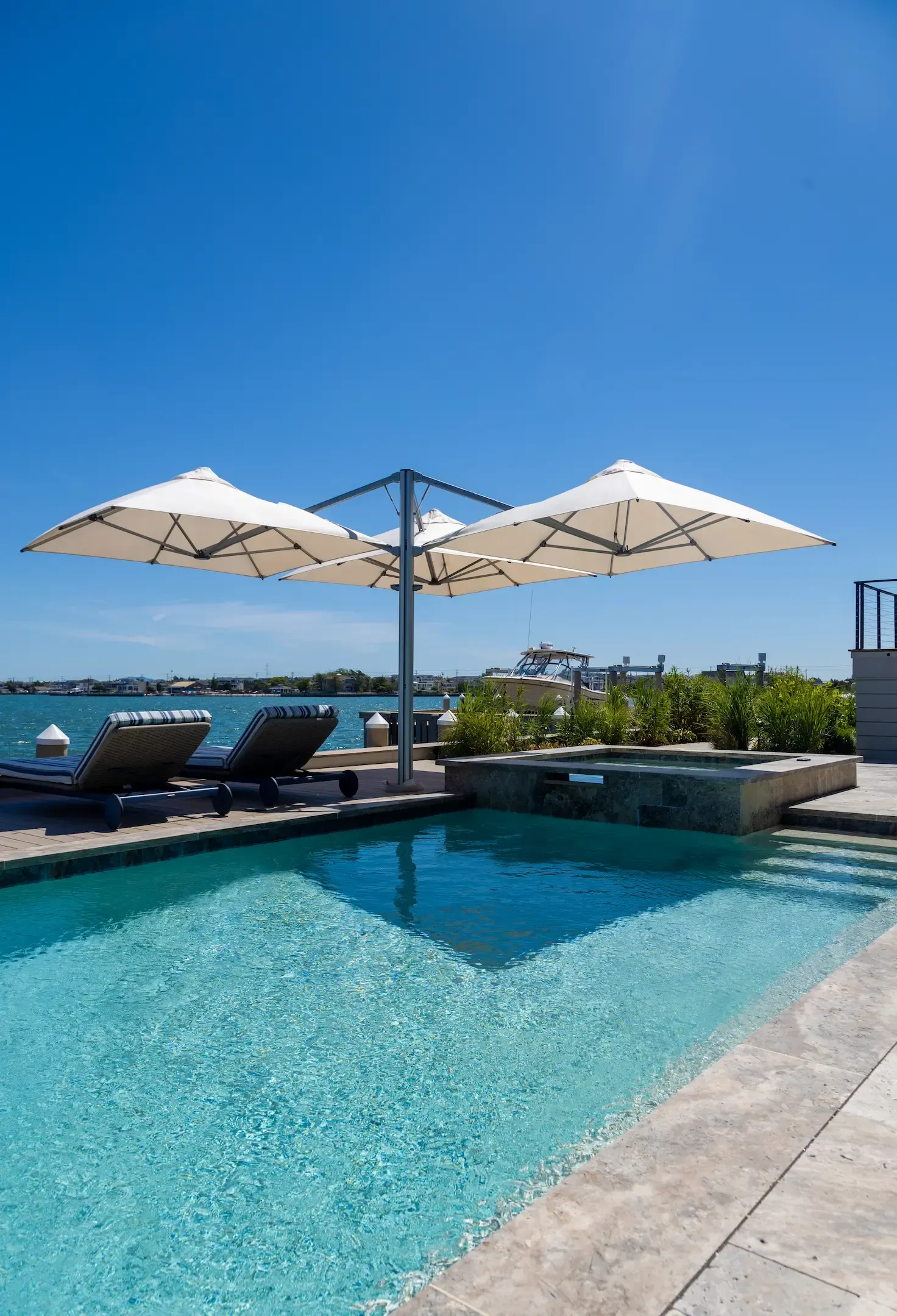 Luxury balcony with a retractable awning, a panoramic lake view, furnished with lounge chairs and a table.