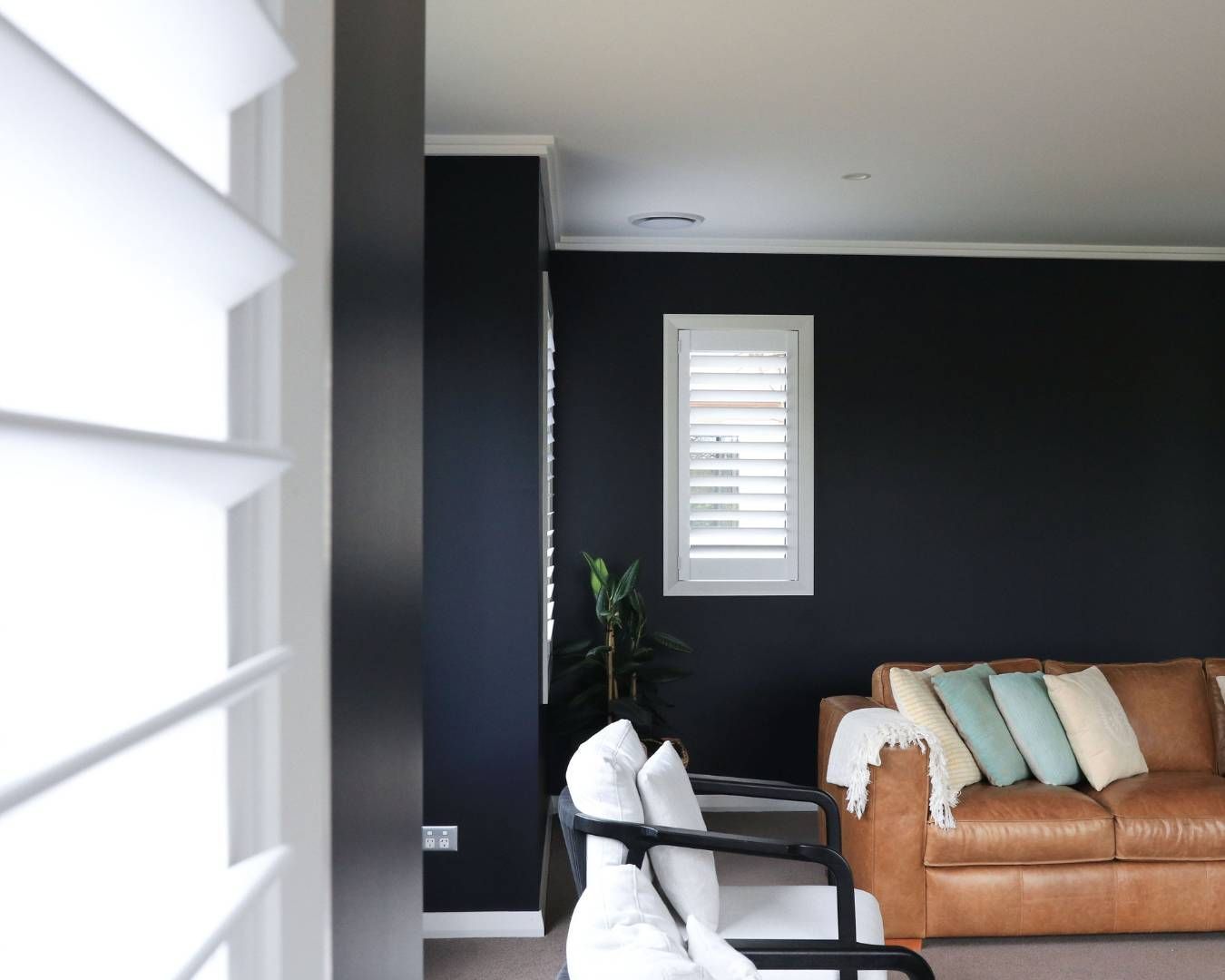 A living room with a brown couch and white chairs