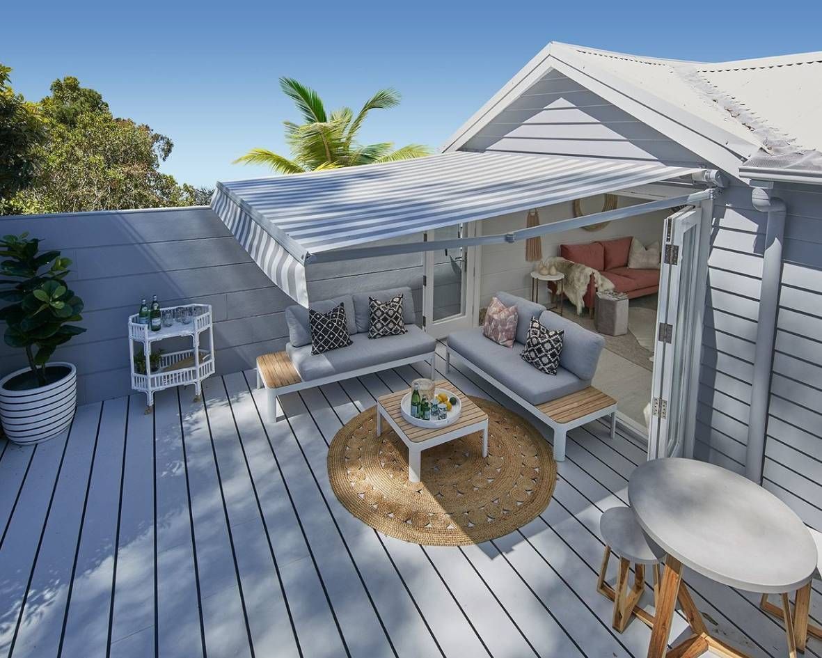 Sunlit outdoor deck with a retractable awning, featuring comfortable seating and a table.
