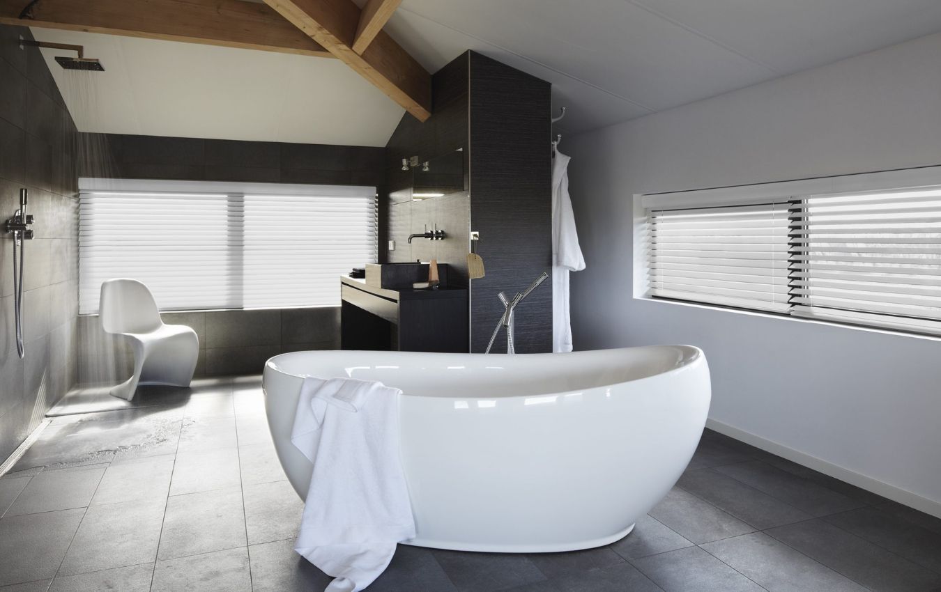 A bathroom with a tub and a chair in it and venetian blinds