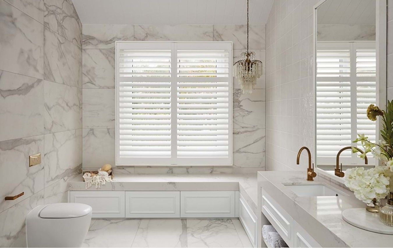 A bathroom with a toilet , sink , and window shutters