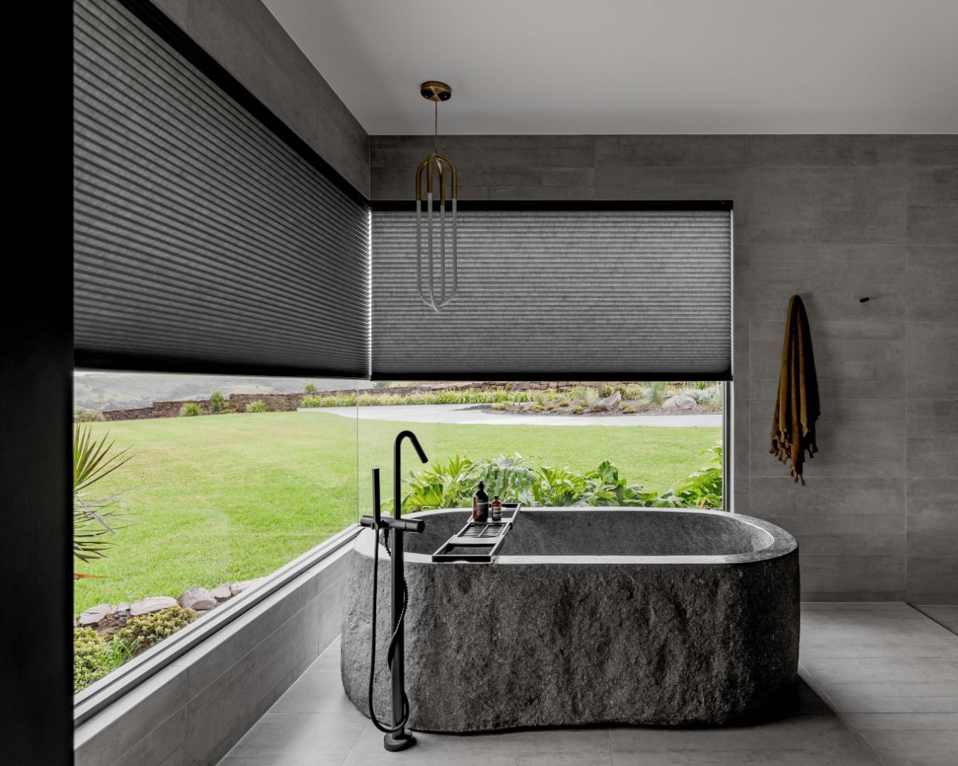 Bathroom with honeycomb blinds, a large window, and a unique stone bathtub.