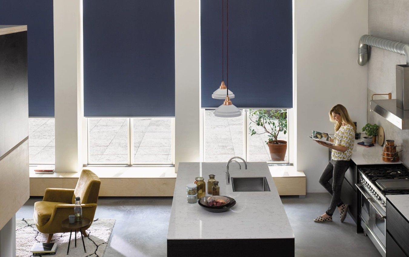 A woman is standing in a kitchen reading a book.
