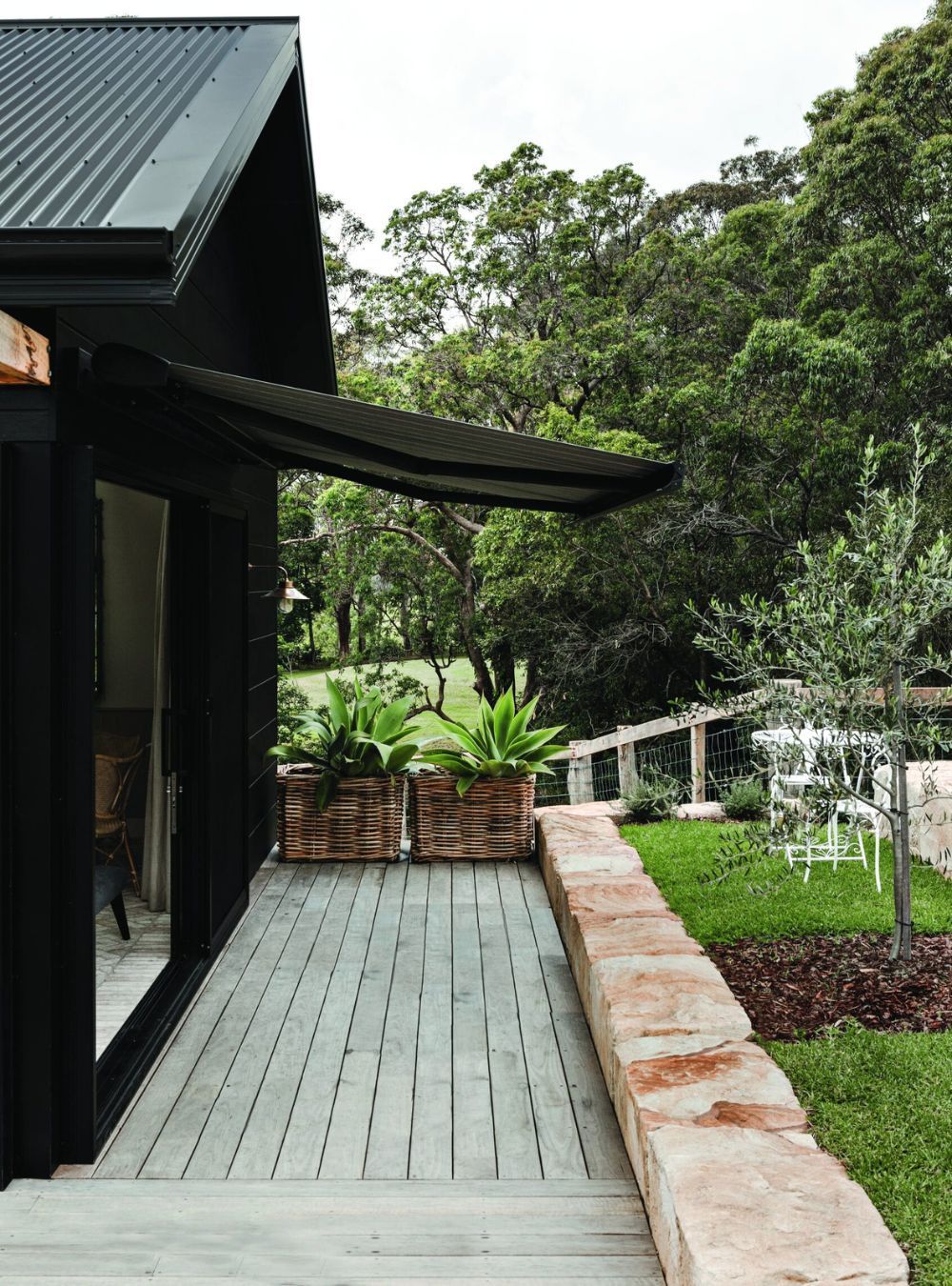 A black house with a wooden walkway leading to it.