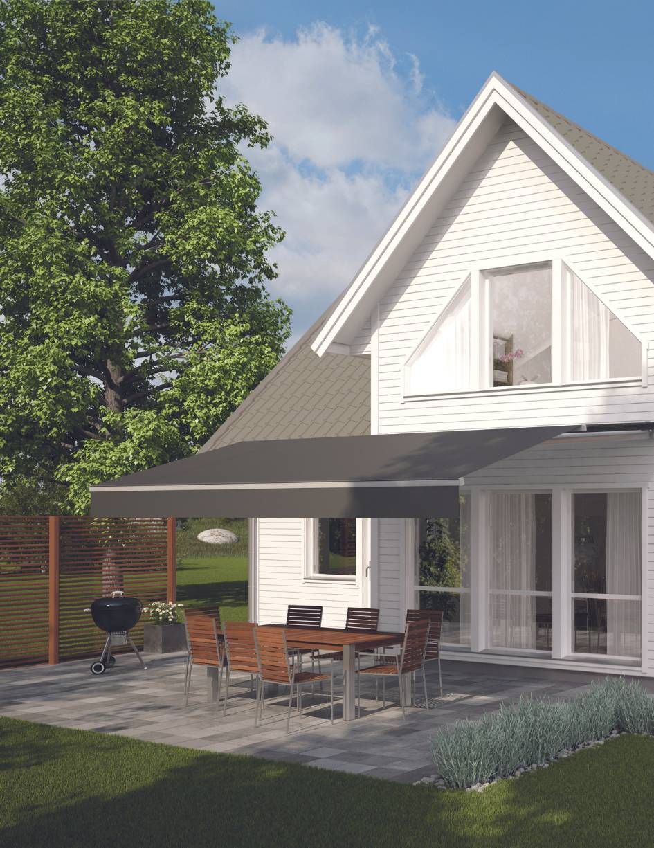 A white house with a patio with a table and chairs under an awning