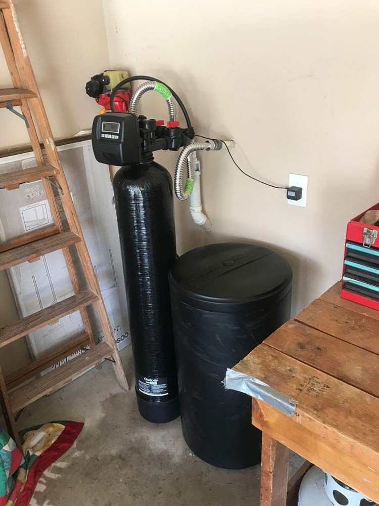 A water softener is sitting next to a wooden table in a room.