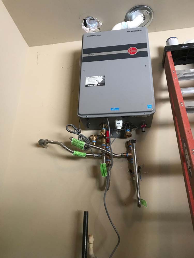 A water heater is hanging on a wall next to a ladder.