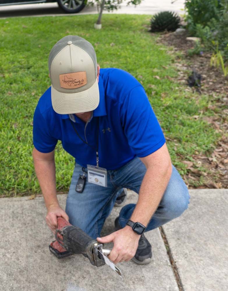 A man in a blue shirt and hat is kneeling down on the sidewalk