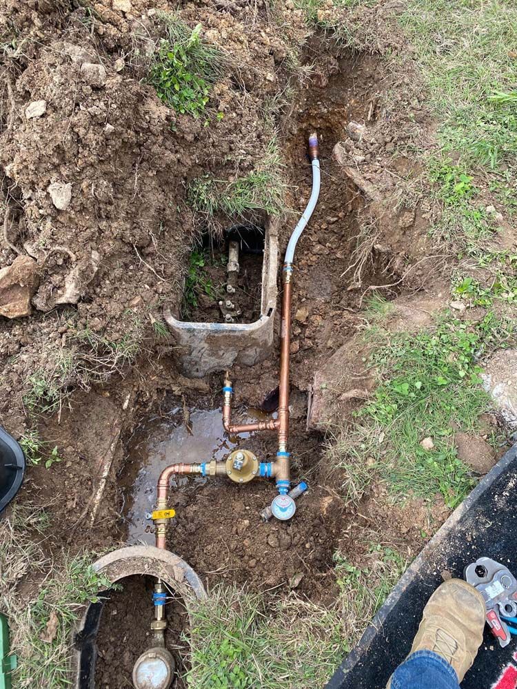 A person is digging a hole in the ground to install a water meter.