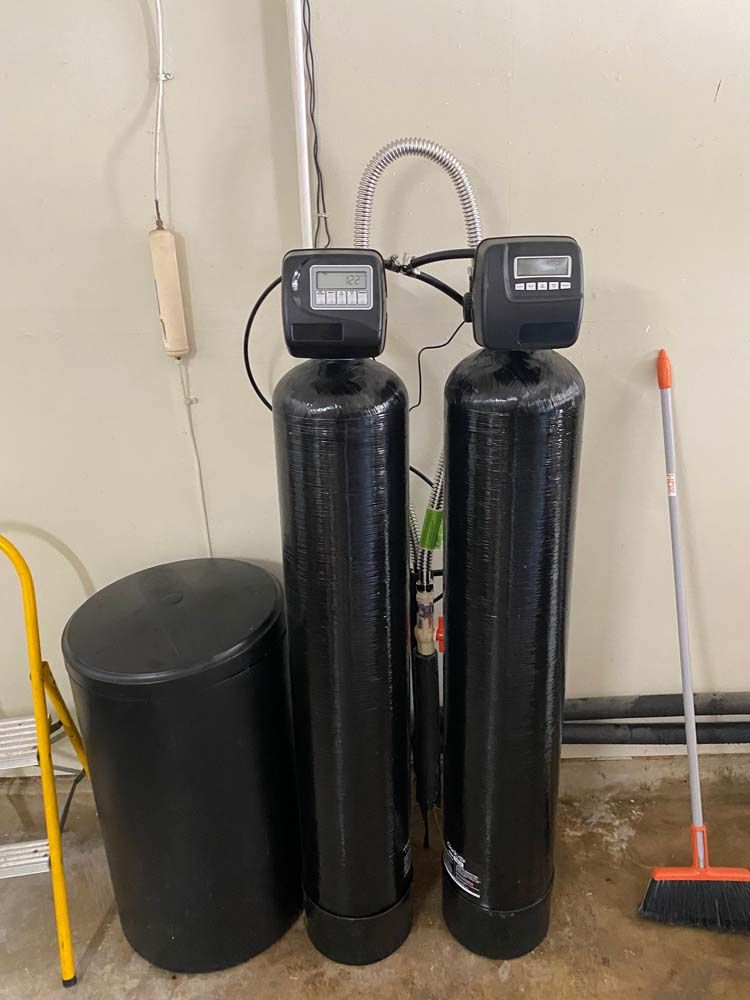 Two black water filters are sitting next to each other in a garage.