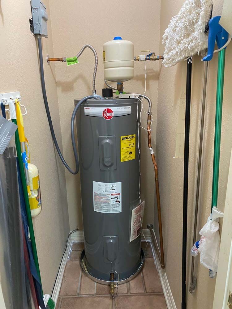 A water heater is sitting in a room next to a mop.