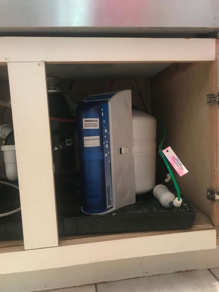 A water filter is sitting under a sink in a cabinet