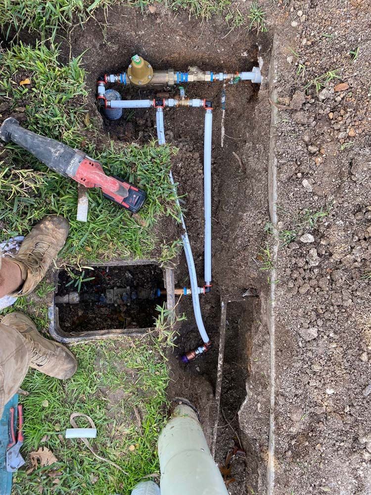 A man is working on a water meter in the dirt.