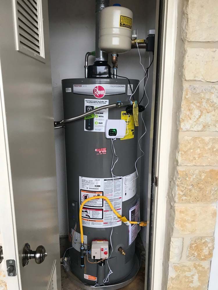 A water heater is sitting in a closet next to a door.