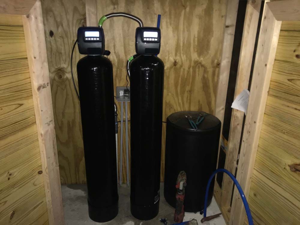 Two black water filters are sitting in a wooden room.