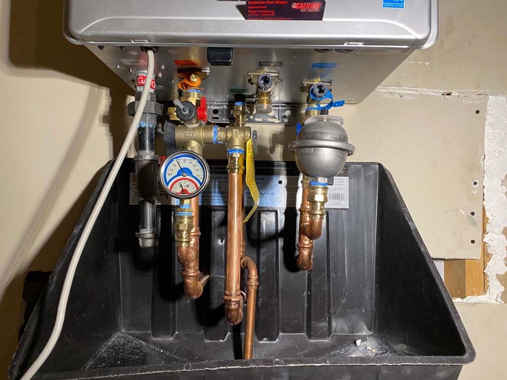 A water heater with copper pipes and valves attached to it