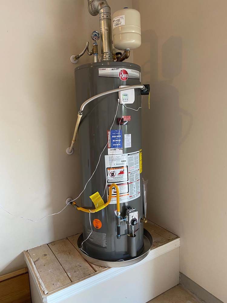 A water heater is sitting in a corner of a room.