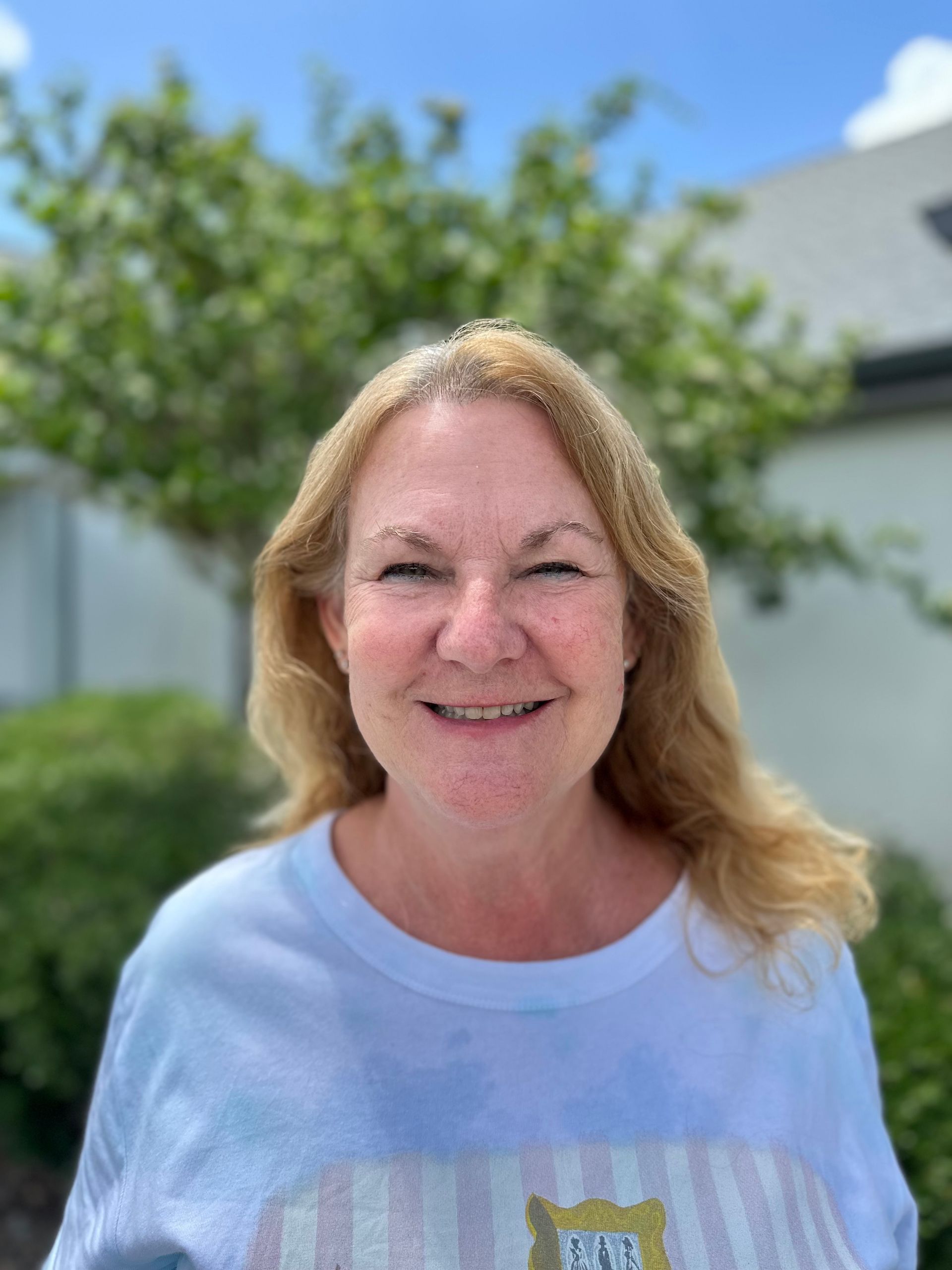 A woman in a white shirt is smiling for the camera.