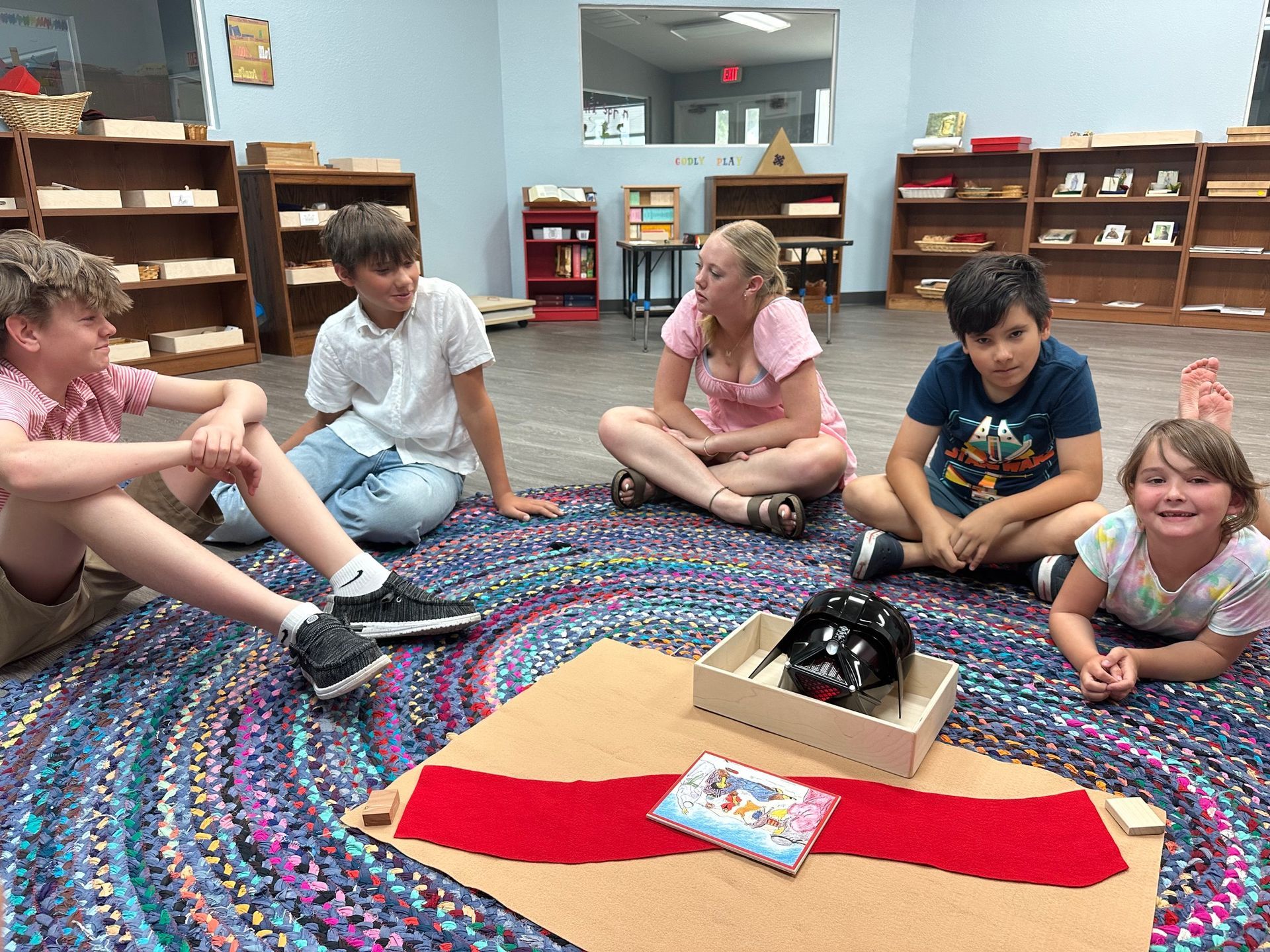 A group of children are sitting on the floor in a circle.