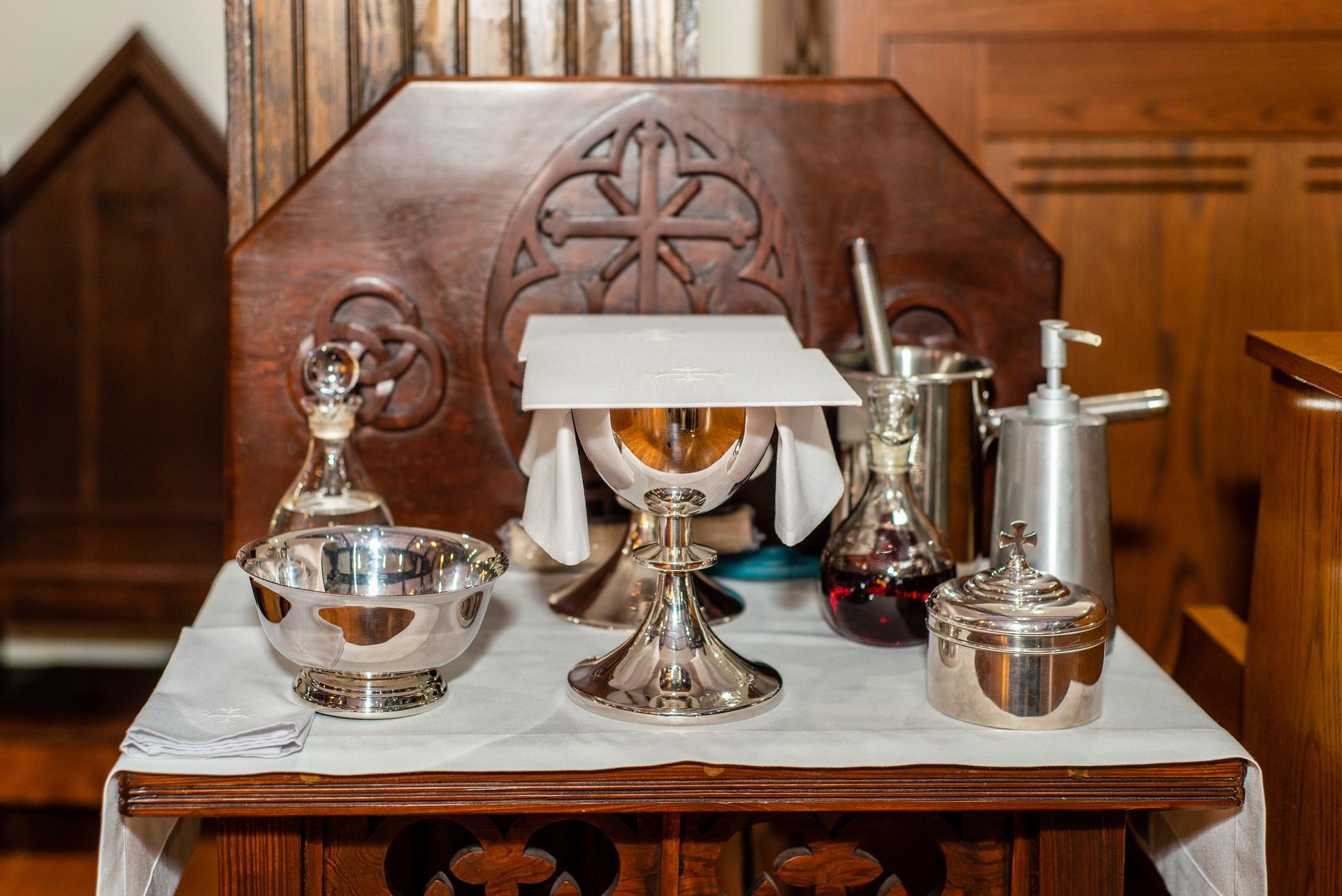 A wooden altar with a chalice , bowls , and bottles on it.