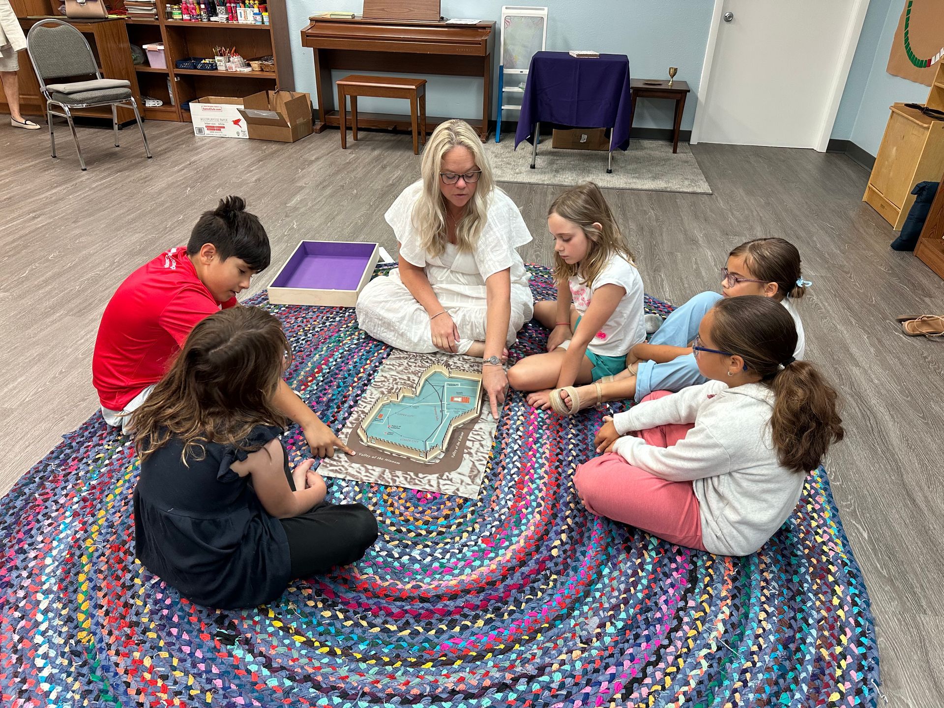 A group of children are sitting in a circle on a rug.
