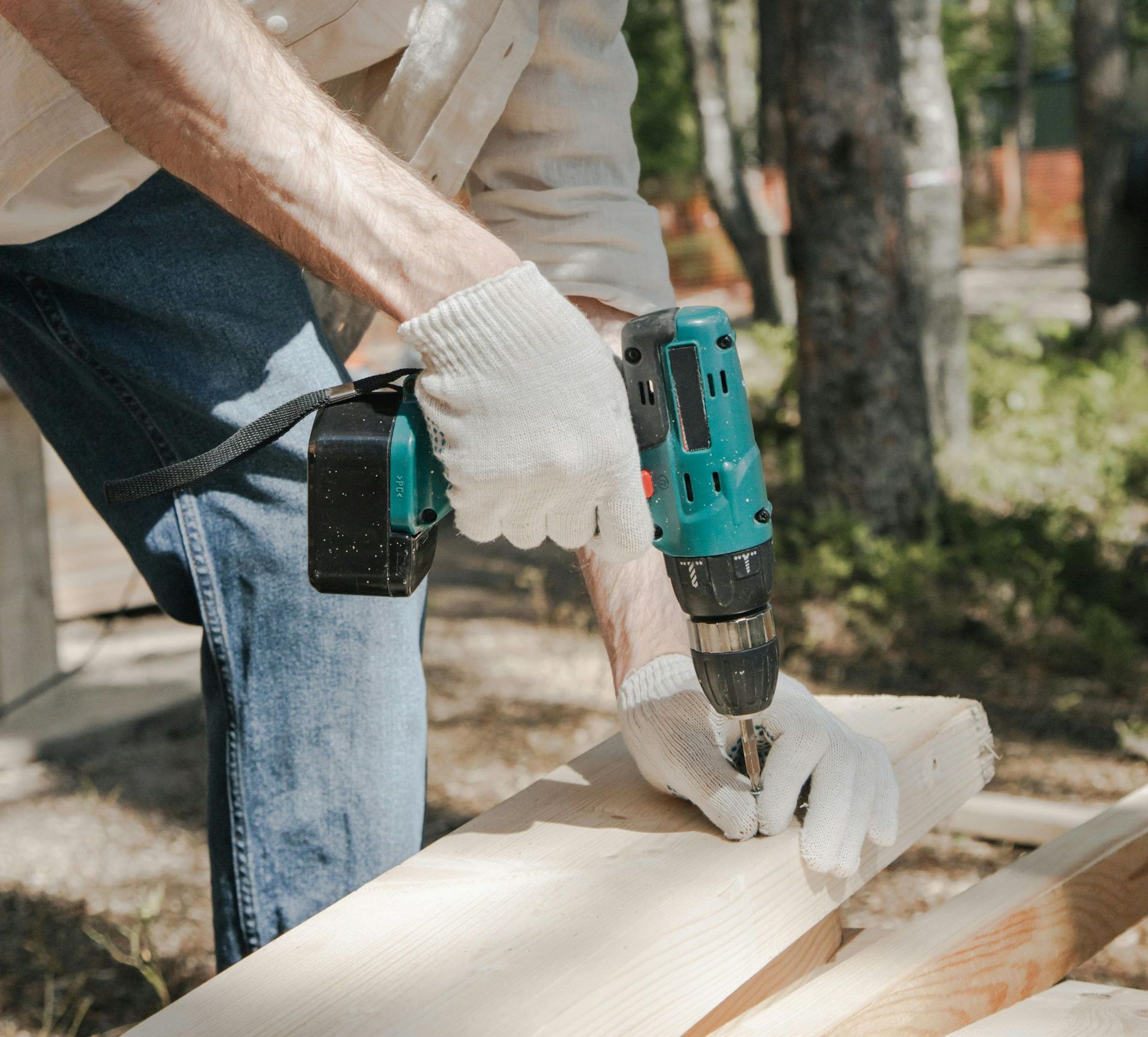 A man is using a drill to drill a hole in a piece of wood.