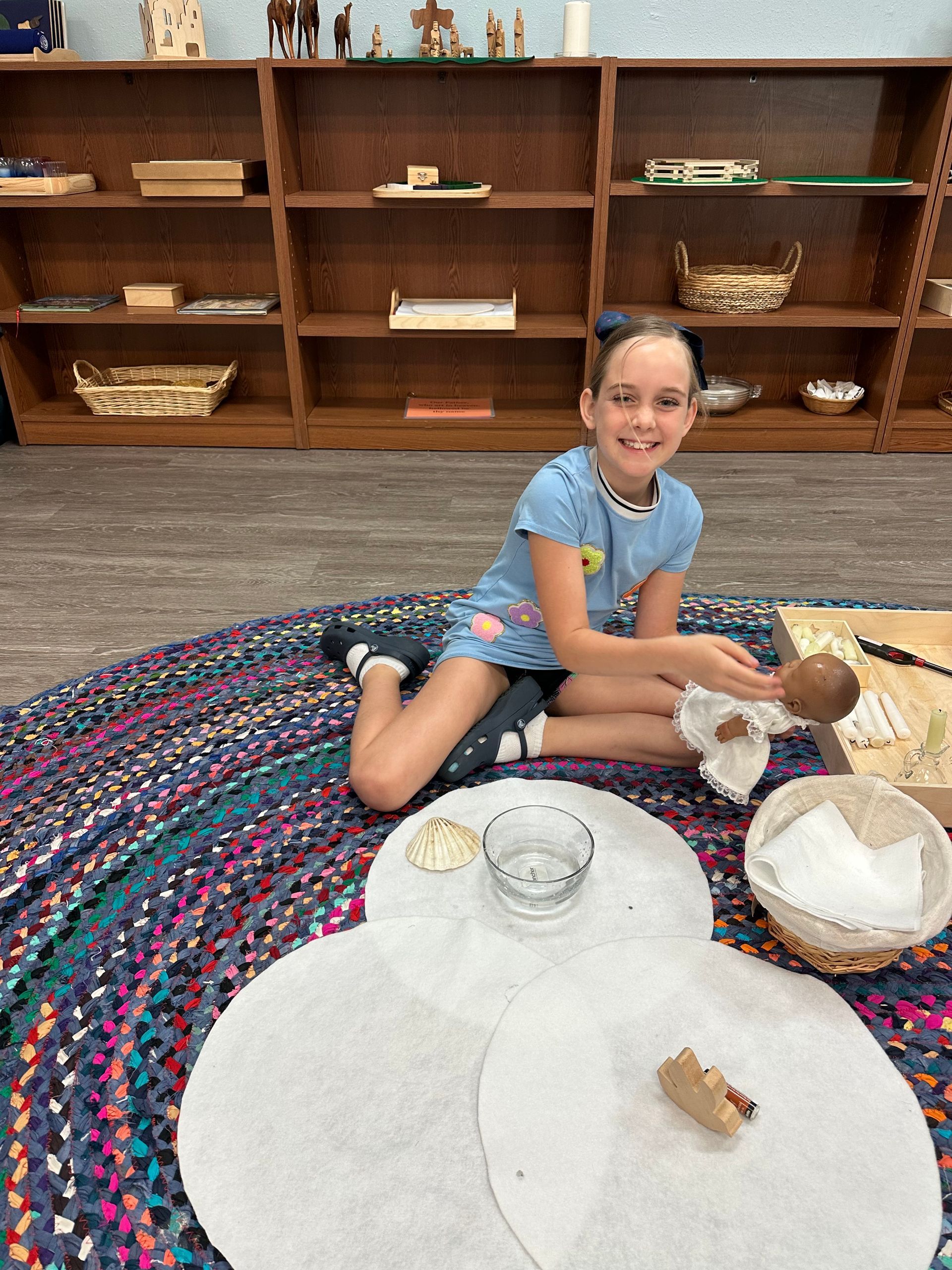 A young girl is sitting on the floor playing with a doll.