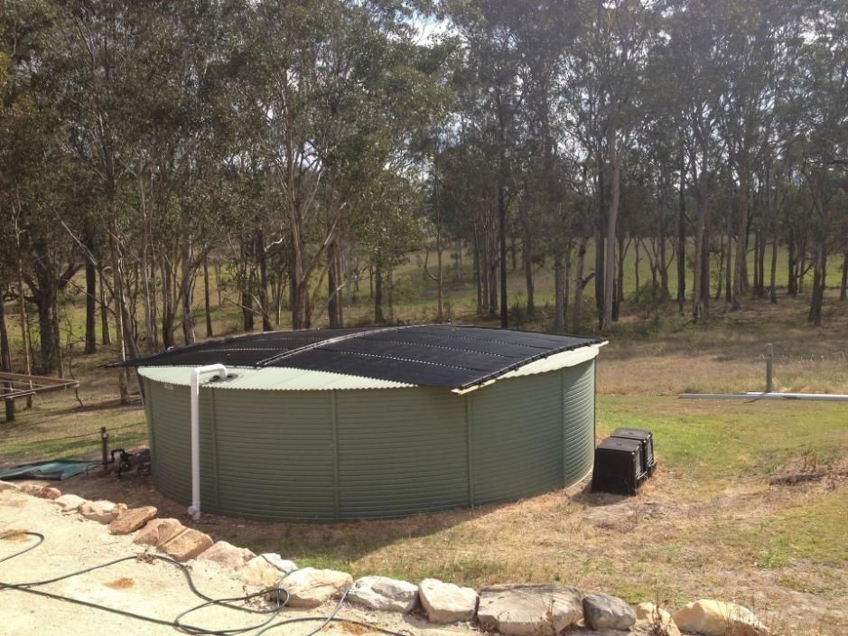 A Large Green Tank is Sitting in the Middle of a Field Surrounded By Trees —  Pool Services in Newcastle